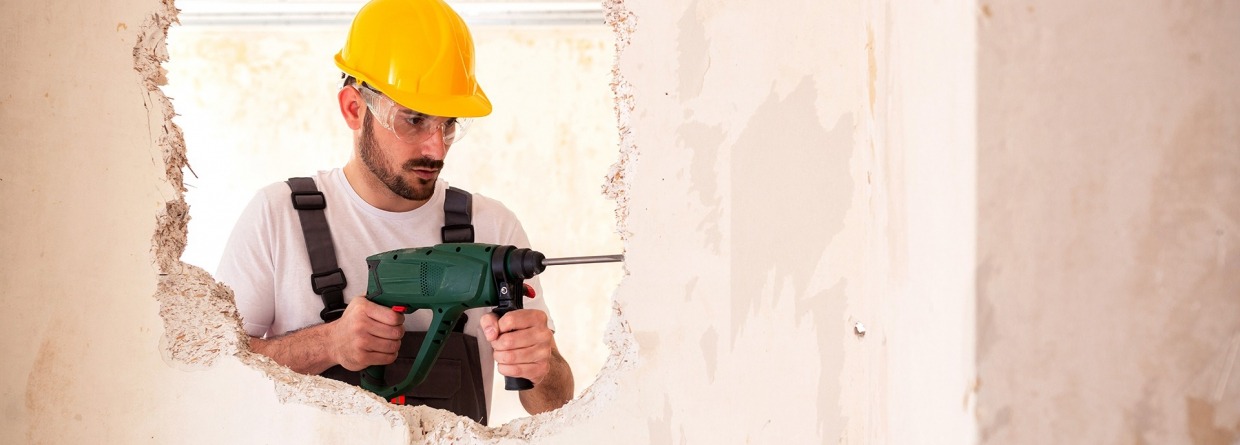 klusjesman, verbouwing, gaten in de muur, klussen, man, verzekeringen, schade zakelijk, gele beschermingshelm